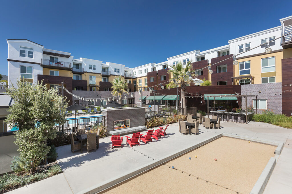 daytime view of fire pit area with bocce ball court with tables and chairs