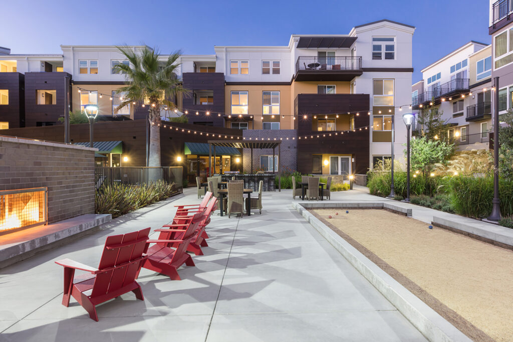 fire pit area with bocce ball court, tables and chairs, and view of building