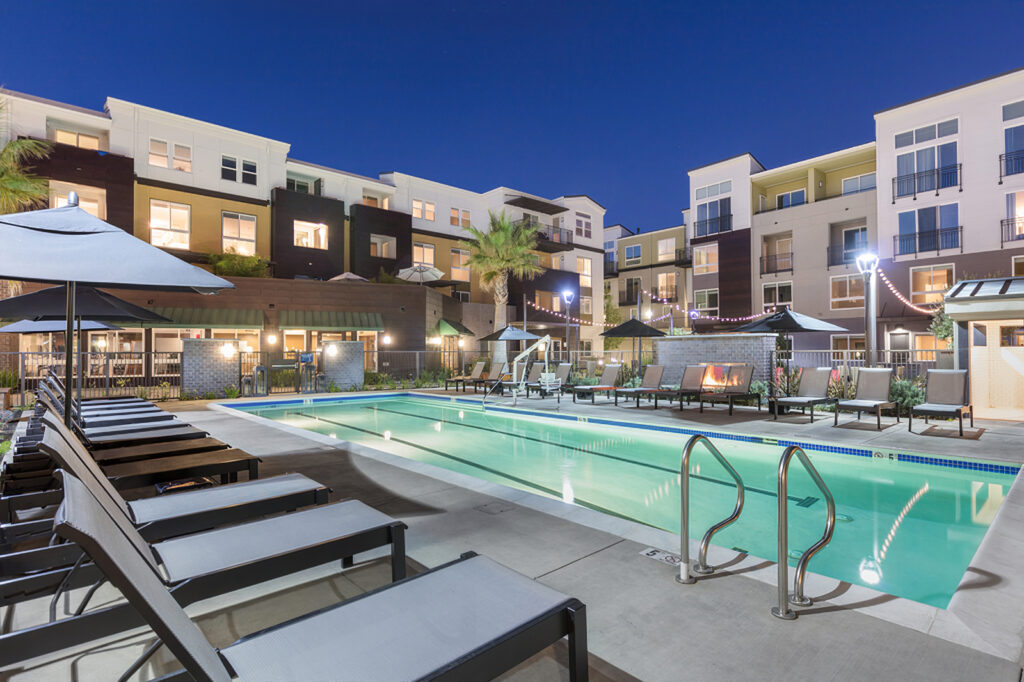 nighttime pool view with loungers and view of fire pit