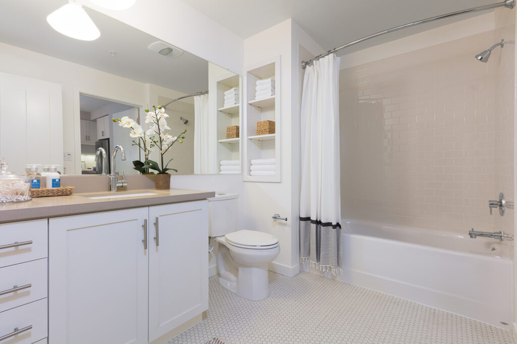 bathroom with single sink, toilet, tub, and large mirror with decor