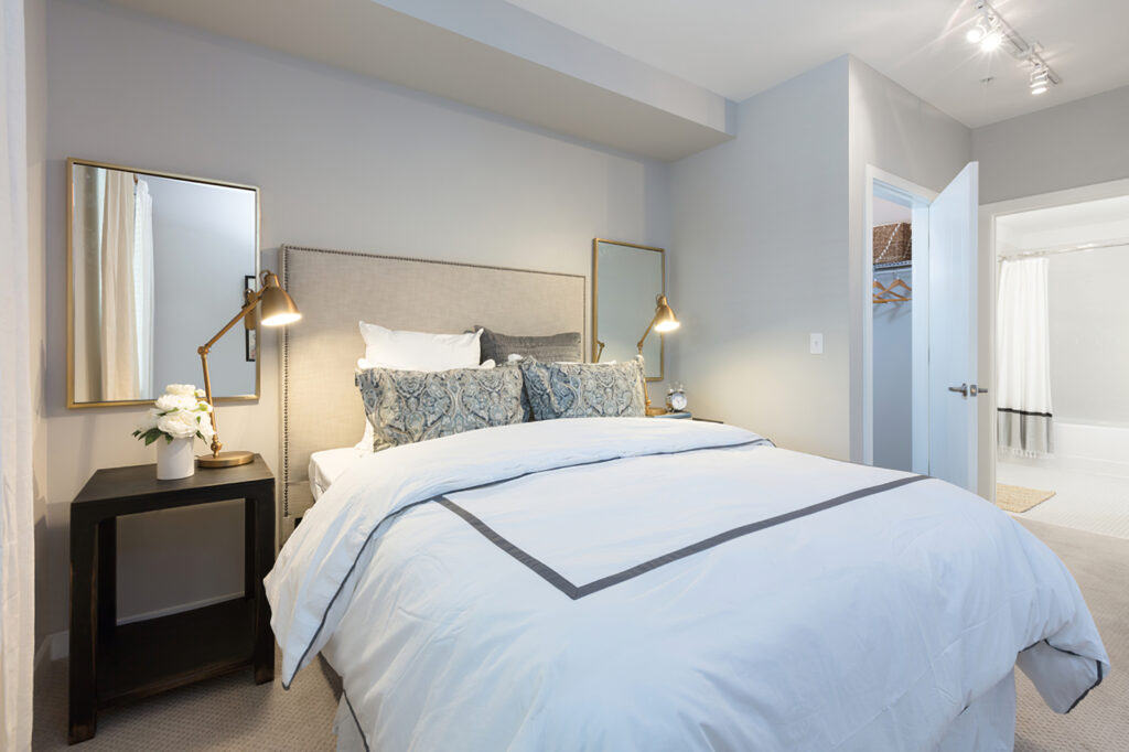 bedroom with bed, decor, and view of bathroom with track lighting