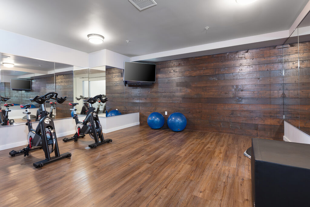 spin room with wood flooring, mirrors, and exercise bikes