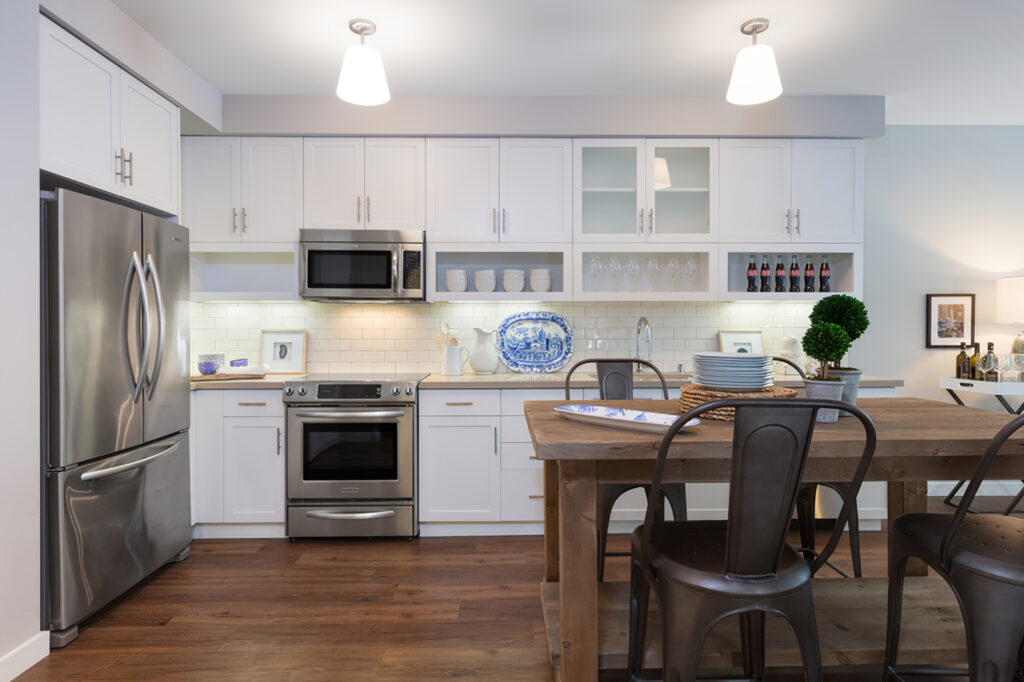 view of open kitchen area with decor, white cabinets, dining table, stainless steel appliances, and wood flooring