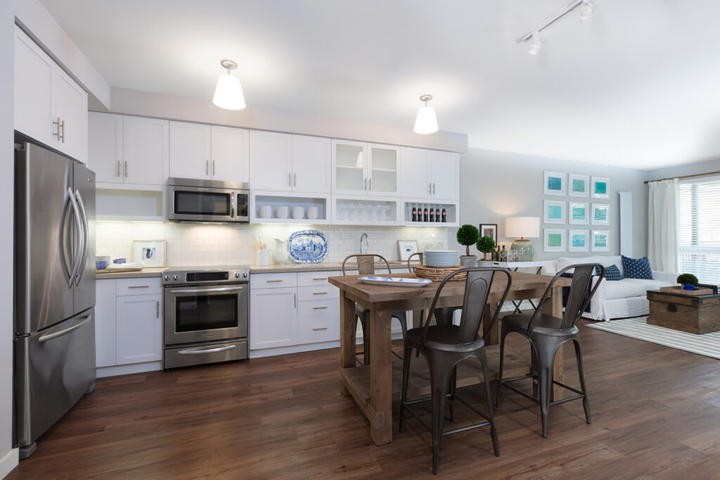 open kitchen area with decor, white cabinets, dining table, stainless steel appliances, and wood flooring