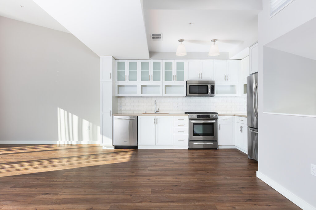 open kitchen are with white cabinets, stainless steel appliances, and wood flooring